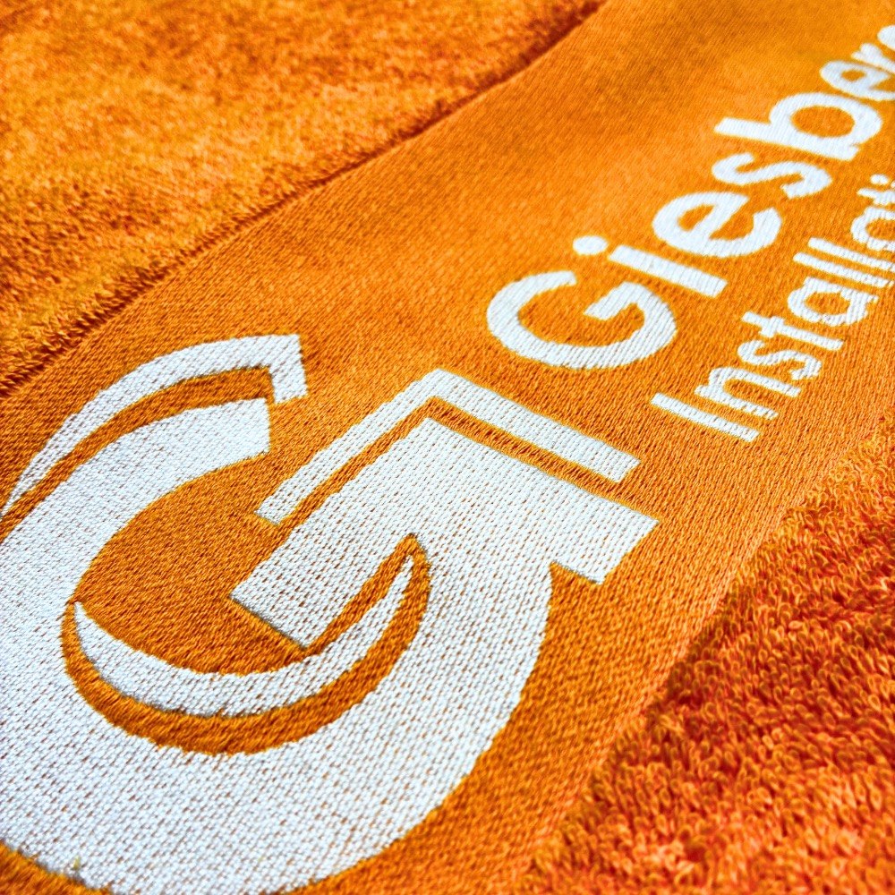 Handtuch Bordüreneinwebung in Orange: Logo und Schriftzug in Weiß eingewebt